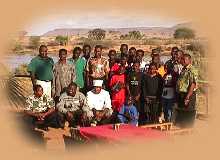 Camp staff with the Orphans around the breakfast table with the Galana River in the background.